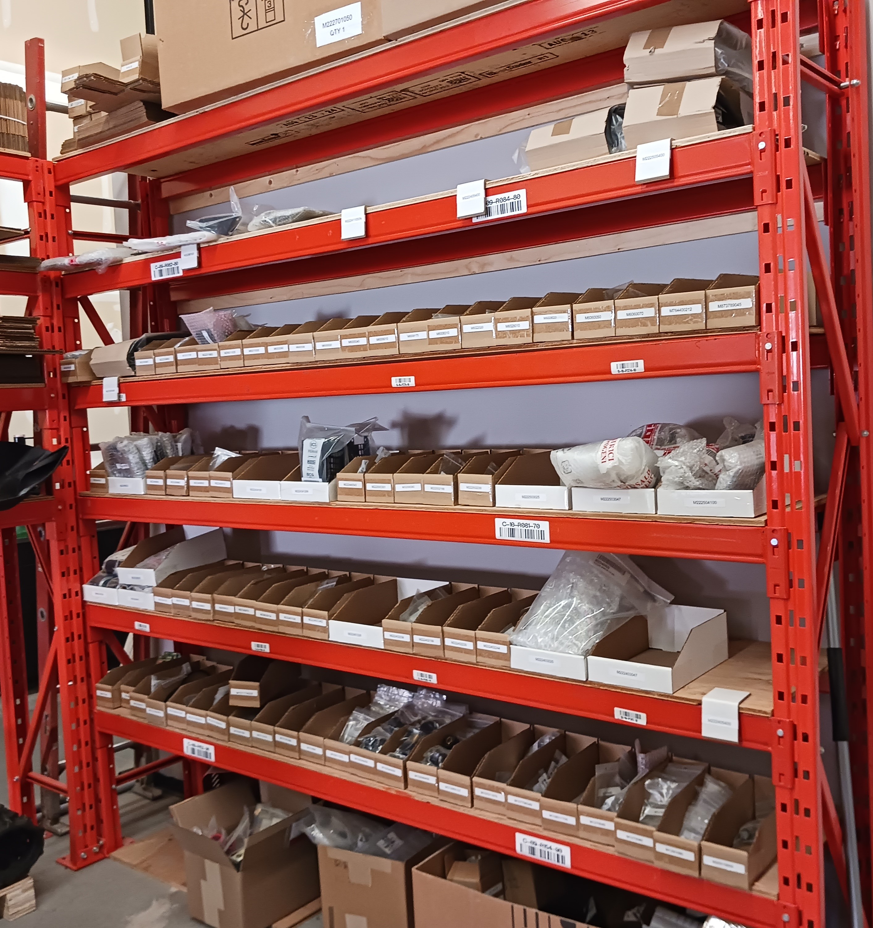 Warehouse racking stocked with labeled bins of original Stryker welder parts