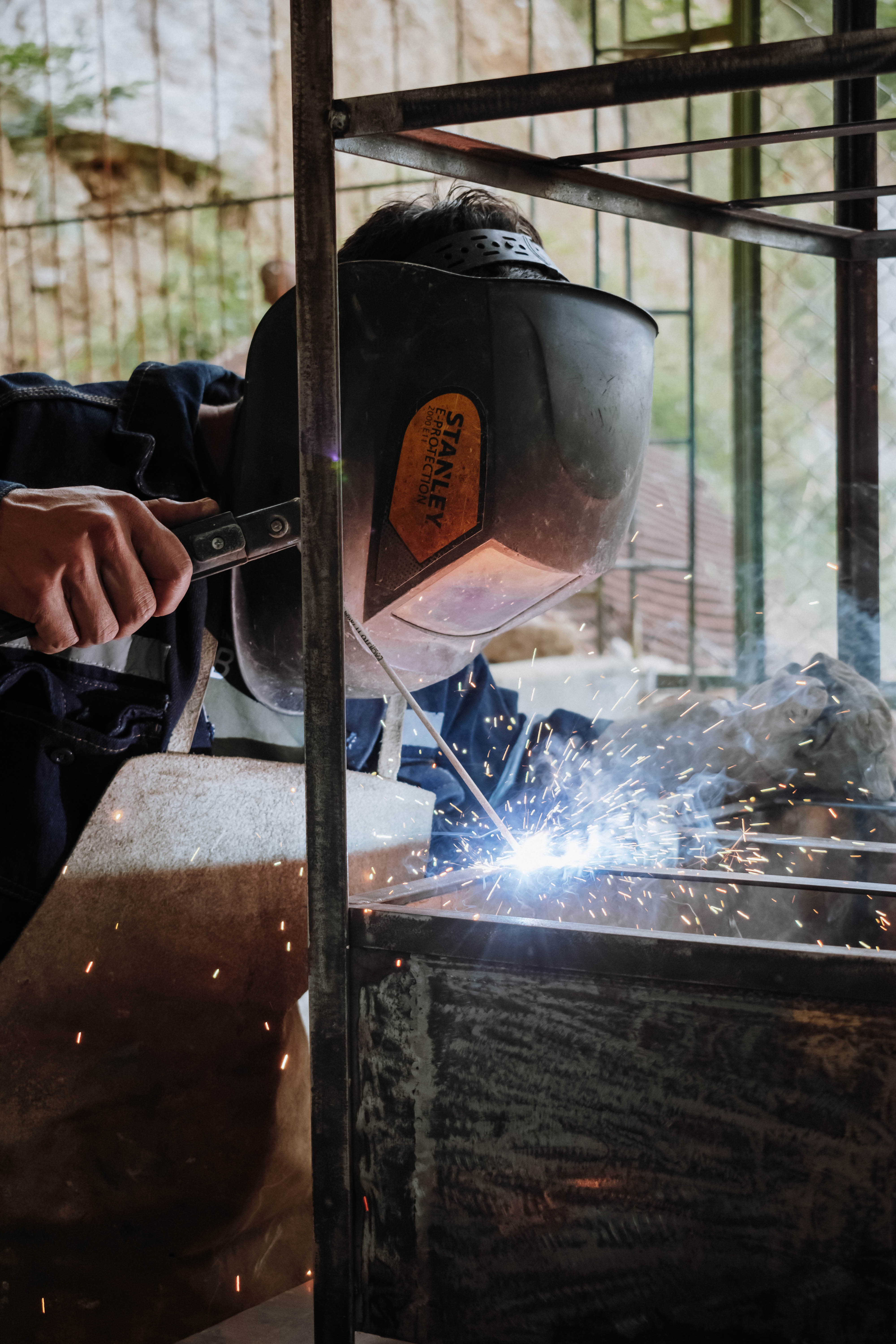 Welder in a protective helmet striking an arc with sparks flying